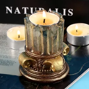 Portavelas retro de columna romana con acabado dorado metálico y velas encendidas.
