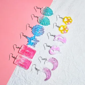Vista dettagliata di orecchini in resina fai-da-te in varie forme glitterate di cuori e zampe.
