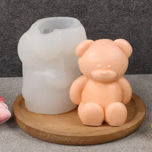 Detailed view of a 3D bear silicone mold and a finished peach wax bear on a wooden tray