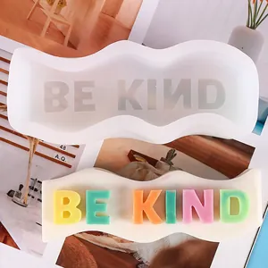 Detailed view of the BE KIND slogan wavy silicone mold and finished colorful soap bar