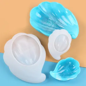 Close-up of shell-shaped silicone mold with finished blue marbled resin storage trays
