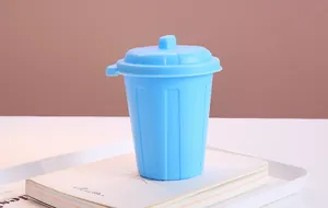 Blue miniature desktop trash can used as a creative pen holder on a white desk