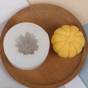 Dettaglio dello stampo in silicone a zucca 3D con candela gialla su un piatto di legno