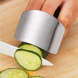 Close-up of stainless steel finger guard protecting hand while slicing cucumber