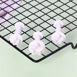 Detailansicht von 3 weißen sternförmigen Fondant-Ausstechern mit Federkolben auf Gitter.