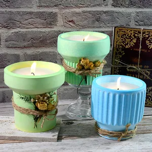 Three scented candles in colorful textured pots with dried flower accents