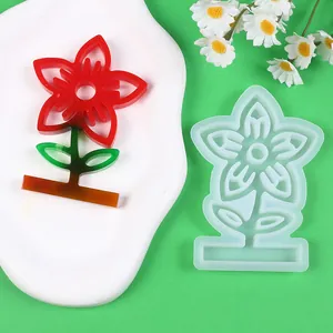 Detail showing flower silicone mold and finished red resin ornament on green surface.