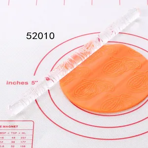 Acrylic embossed rolling pin creating intricate leaf patterns on orange fondant dough