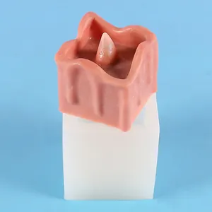 Dettaglio dello stampo in silicone quadrato e candela di cera rosa finita su sfondo blu