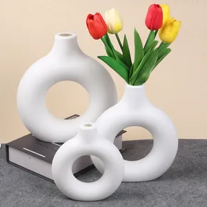 Set of three minimalist white donut-shaped plastic vases decorated with bright tulips.