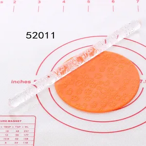 Macro view of clear acrylic rolling pin with embossed flower patterns on orange fondant