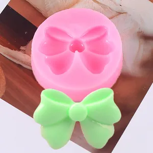 Dettaglio di uno stampo in silicone rosa a fiocco con un fiocchetto verde in pasta