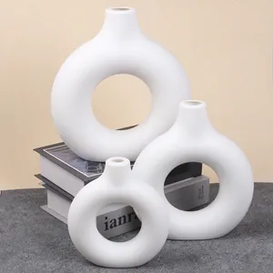 Set of three white minimalist donut ceramic vases arranged on books for home decor