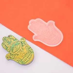 Dettaglio macro dello stampo in silicone mano di Hamsa accanto al sottobicchiere in resina