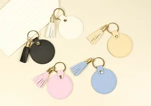 Vue détaillée de porte-clés circulaires en cuir coloré avec pompons en tons pastel.