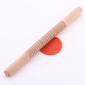 Dettaglio del mattarello in legno filettato per creare motivi sulla pasta frolla.
