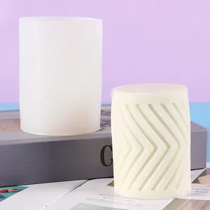 Nahaufnahme einer zylindrischen Silikonform neben einer fertigen Chevron-Muster-Kerze