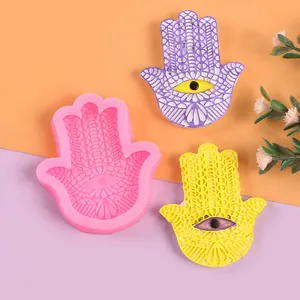 Dettaglio dello stampo in silicone a mano di Hamsa con campioni di resina viola e gialla