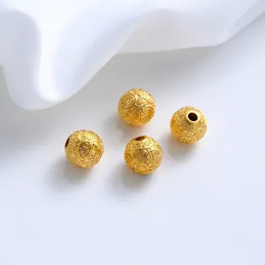 Macro view of gold-plated spacer beads with intricate traditional engraved patterns
