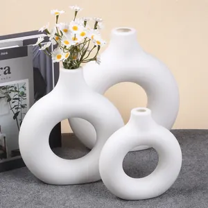 Set of three white donut-shaped plastic vases for minimalist interior decoration