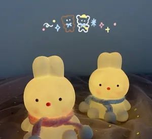 Close-up of cute rabbit LED night lights featuring warm glow and colorful knitted scarves