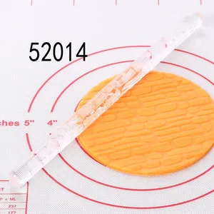 Detailed view of clear acrylic rolling pin creating brick patterns on orange fondant