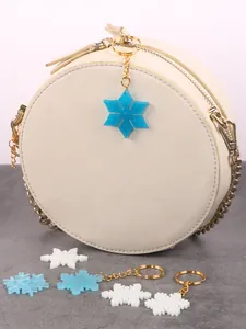 Close-up of DIY snowflake pendants used as stylish charms for cream-colored round bags