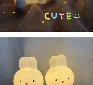 Close-up of two glowing cute bunny LED night lights set against a starry mesh background