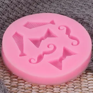 Close-up view of a pink silicone mold featuring necktie, bowtie, and mustache cavity designs