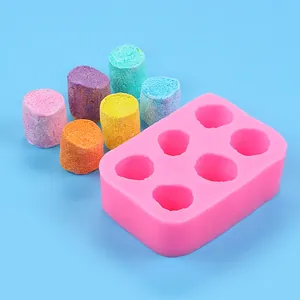 Detail of pink marshmallow silicone mold with colorful DIY squishy toy samples on blue