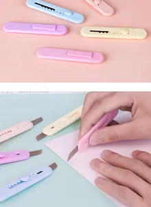 Close-up view of a mini retractable utility knife being used on paper for craft work