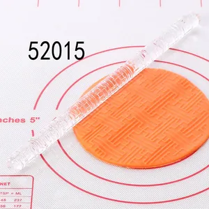 Close-up of clear acrylic textured rolling pin embossing geometric pattern on orange fondant
