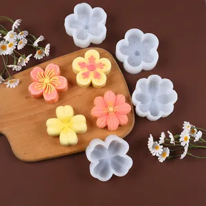 Detail view of flower shaped silicone molds and finished floral cakes on a wooden board