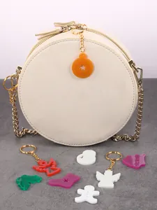 Colorful acrylic Christmas charms shown as keychains attached to a white circular bag