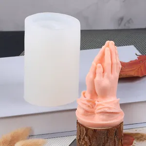 Vue détaillée du moule en silicone à côté d'une bougie mains en prière couleur pêche