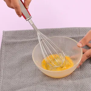 Frusta manuale in acciaio inox con manico in silicone che sbatte uova in ciotola