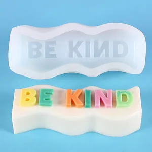 Detailed view of wavy silicone mold and finished 'BE KIND' colorful slogan soap
