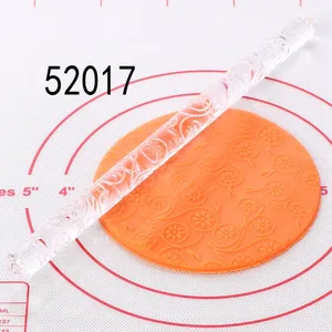 Detail view of acrylic rolling pin creating floral patterns on orange fondant