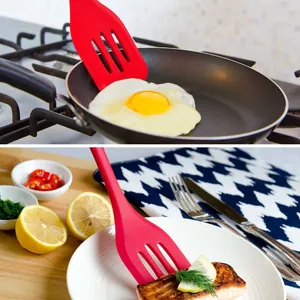 Red heat-resistant silicone slotted turner used for frying eggs and serving cooked salmon steak