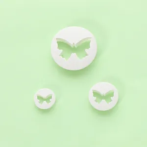 Set van drie witte vlindervormige fondant uitstekers op een lichtgroene achtergrond