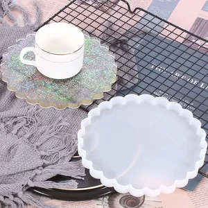 Detalle de un molde de silicona blanco festoneado junto a un posavasos de resina brillante