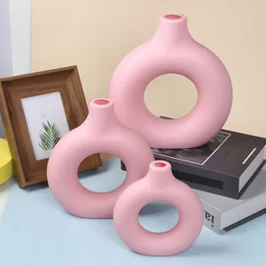 Three sizes of pink donut vases arranged with minimalist decor books and frame