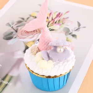 Close-up detail of blue muffin cup liner decorated with pink mermaid tail and seashell ornament