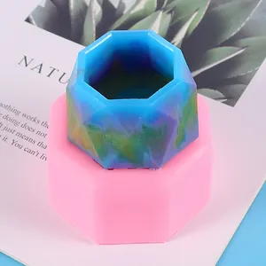 Close-up detail of a pink silicone mold and a finished hexagonal blue resin flower pot