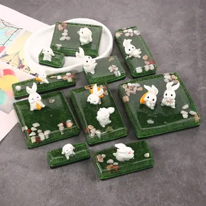 Detail handgefertigter Harzornamente mit weißen Miniaturkaninchen und grünem Gras