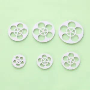 Detailweergave van zes witte pruimenbloesem fondant uitstekers voor taartdecoratie
