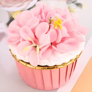 Close-up of a pink muffin cup featuring an elegant gold rolled edge and floral decor