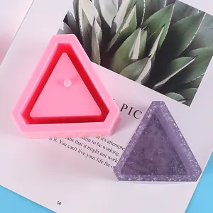 Macro view showing a pink triangular silicone mold alongside a finished purple glitter resin tray.