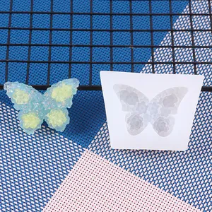 Detailed view of a white butterfly silicone mold beside a sparkly blue resin butterfly