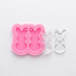 Detail view of pink rabbit silicone mold and clear resin rabbit pendants on a white background